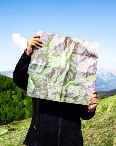 Randonneuse tenant une carte IGN devant les montagnes à Valberg