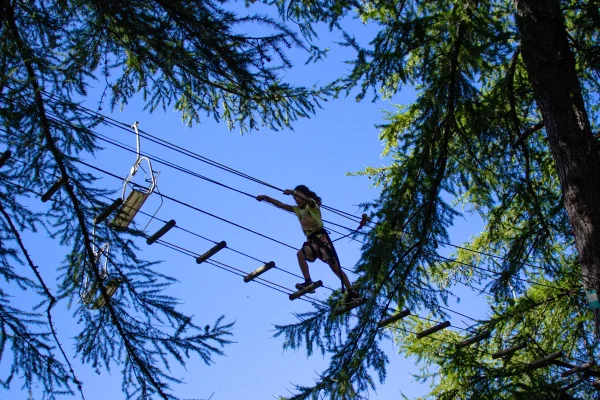 Enfant sur une passerelle dans les arbres sur le parcours Espace Valberg Aventure